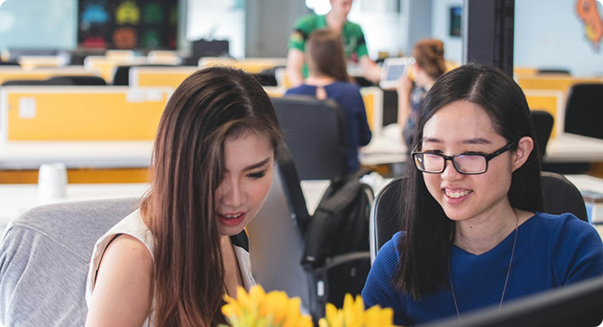 an image of a 2 girls working in a nice office environment in front of their desks happy and fulfilled in their careers in MobileMINDS
